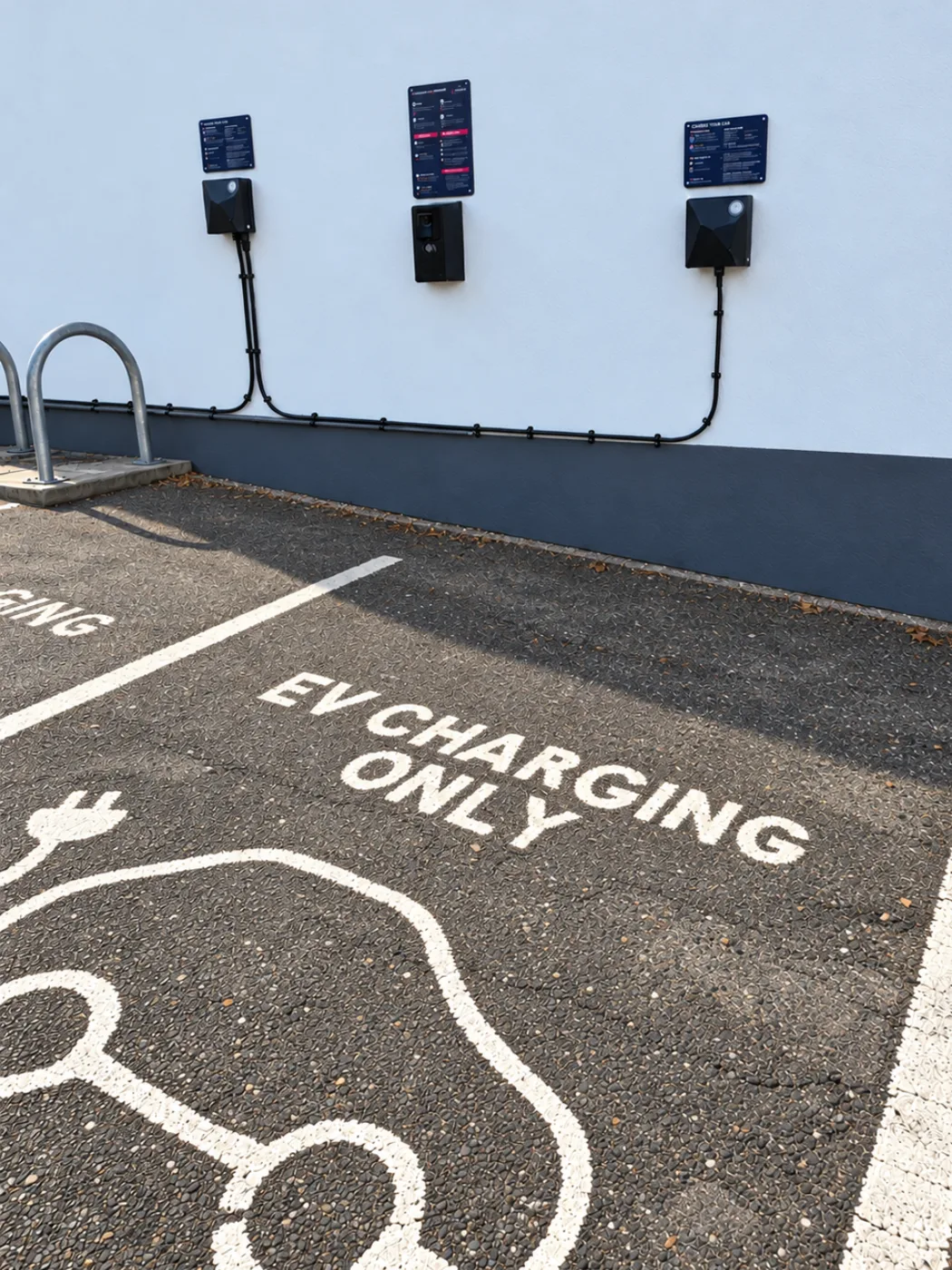 A charging bay marked EV charging only, with wall-mounted chargers and signs above a cycle stand at The Bromley Court Hotel