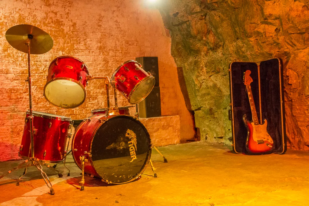 A drum kit and guitar on display in a chalk passage at Chislehurst Caves