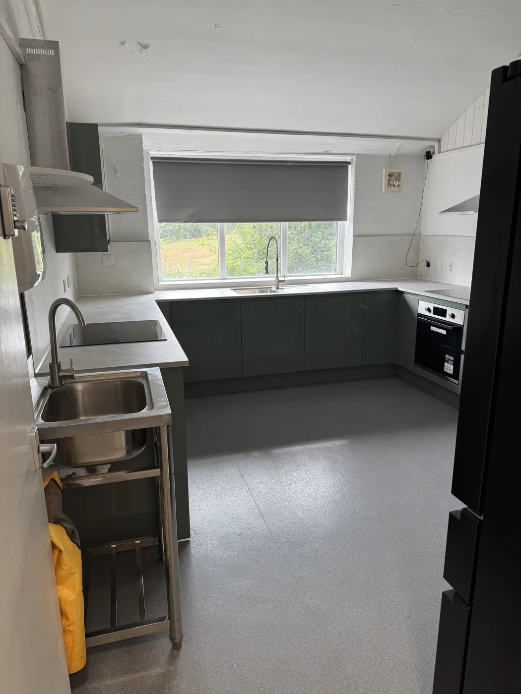 The kitchen at Roots4Learning with dark grey units, an oven, a sink and a window
