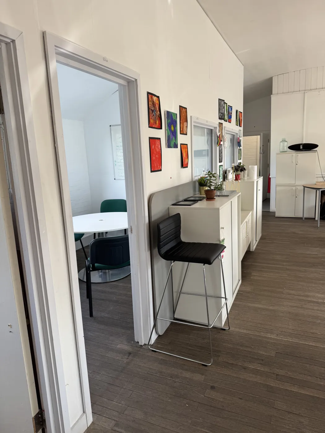 A room at Roots4Learning with student artwork on the walls, a high chair at a counter and a round table